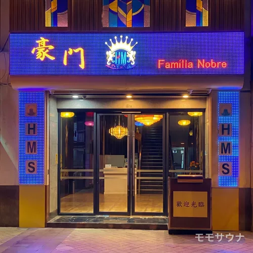 ネオンサインが灯るファミリア・ノーブレの店舗外観、マカオ最大級のサウナ